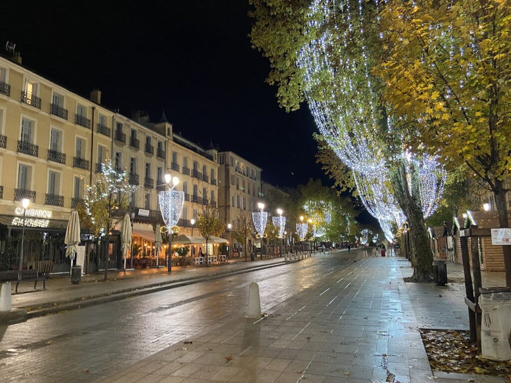 Le cours Mirabeau illuminé un soir de décembre, platanes drapés de guirlandes blanches au-dessus des chalets du marché de Noël