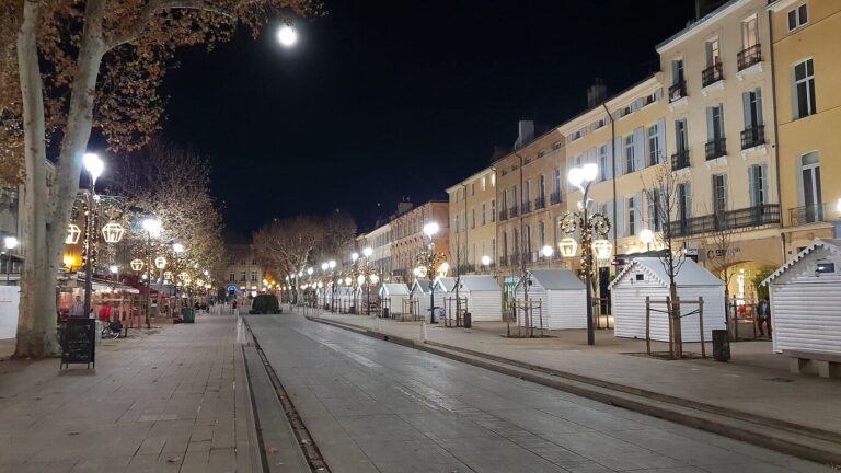 Les chalets blancs du marché de Noël alignés le long des façades du cours Mirabeau, sous les lanternes lumineuses, la nuit