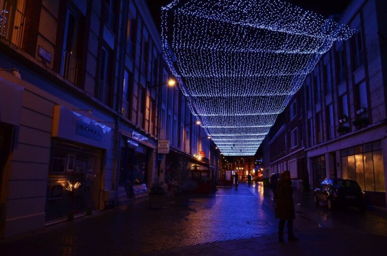 Voûte de guirlandes lumineuses bleues au-dessus d’une rue piétonne d’Amiens, la nuit