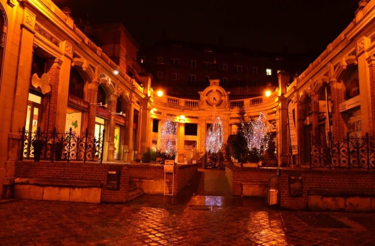 Cour à arcades éclairée de nuit, ornée de sapins lumineux, dans le centre d’Amiens