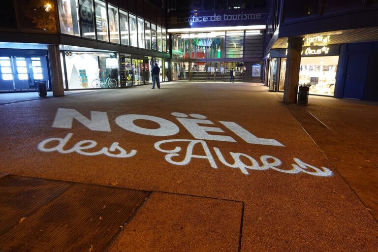 L’inscription « Noël des Alpes » projetée au sol sur le parvis éclairé de l’office de tourisme d’Annecy, la nuit
