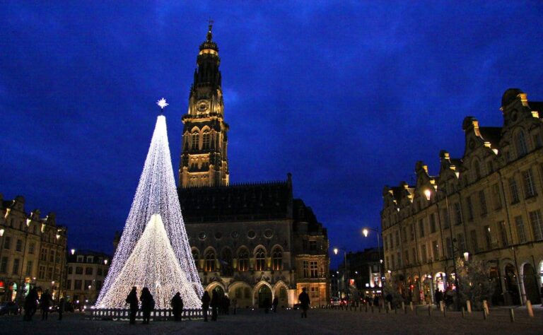 Le beffroi et l’hôtel de ville d’Arras à l’heure bleue, avec un grand sapin lumineux sur la place des Héros