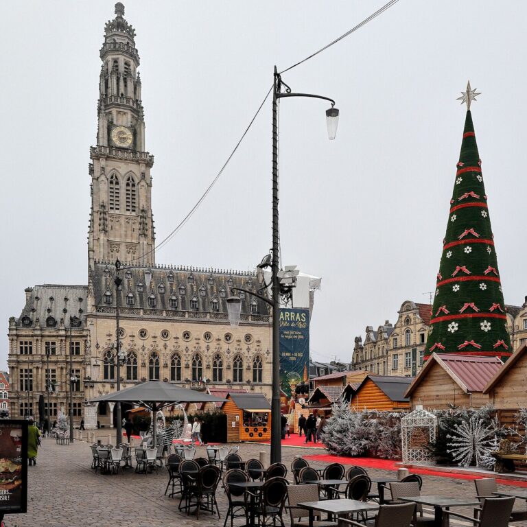 L’hôtel de ville et le beffroi d’Arras en décembre, avec un sapin décoré et des chalets au pied