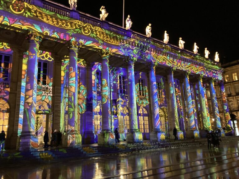 Projection lumineuse colorée sur la colonnade du Grand Théâtre, un soir de pluie avant Noël