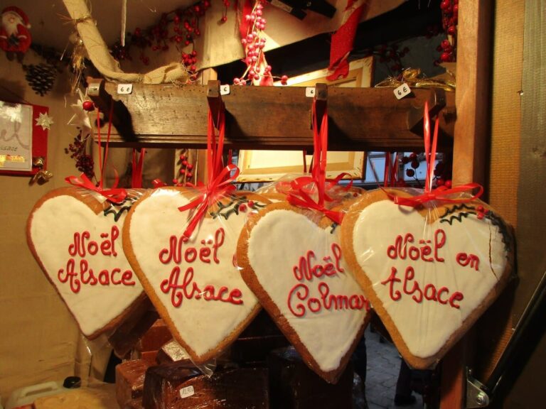 Cœurs en pain d’épices marqués « Noël en Alsace » et « Noël Colmar », suspendus à un chalet