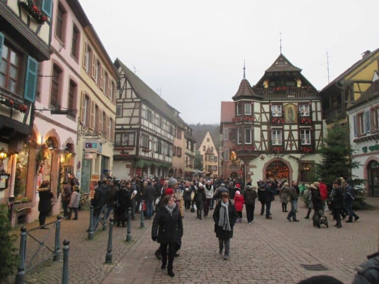 Une rue du centre animée par le marché de Noël, avec une grande maison à colombages au fond
