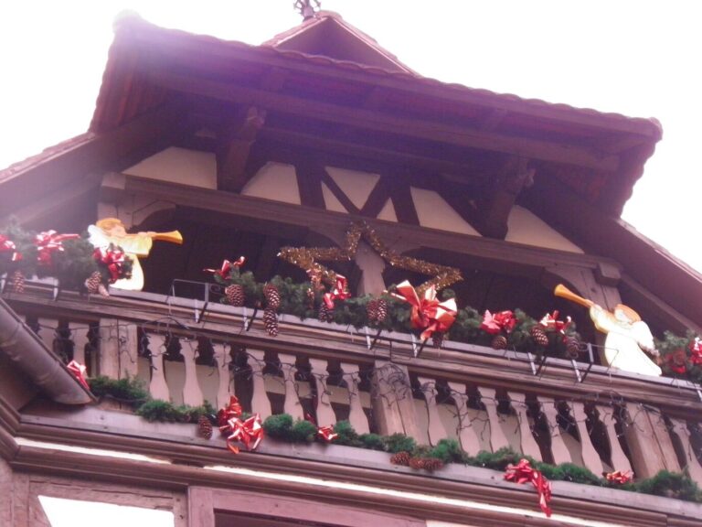Un balcon de bois orné de guirlandes de sapin, de nœuds rouges et d’anges