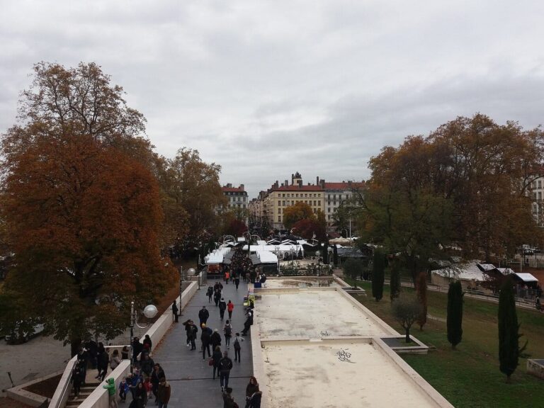 Le marché de Noël de la place Carnot vu depuis l’entrée de la gare de Perrache, avec ses chalets entre les arbres en automne