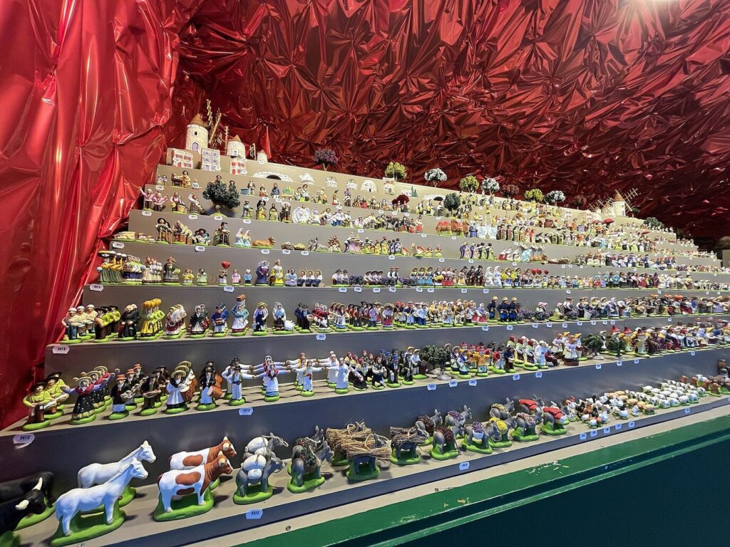 Des centaines de santons de Provence alignés en gradins sous une tente rouge, au marché de Noël du Vieux-Port