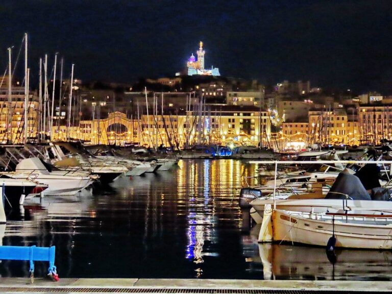 Les bateaux du Vieux-Port et les quais éclairés un soir de décembre, avec Notre-Dame-de-la-Garde illuminée sur sa colline