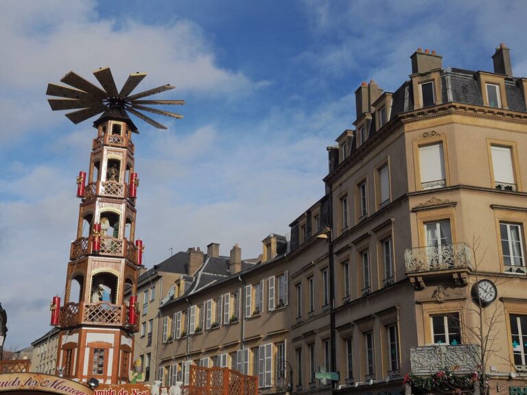 La pyramide de Noël du marché de Metz devant des façades en pierre jaune, sous un ciel bleu