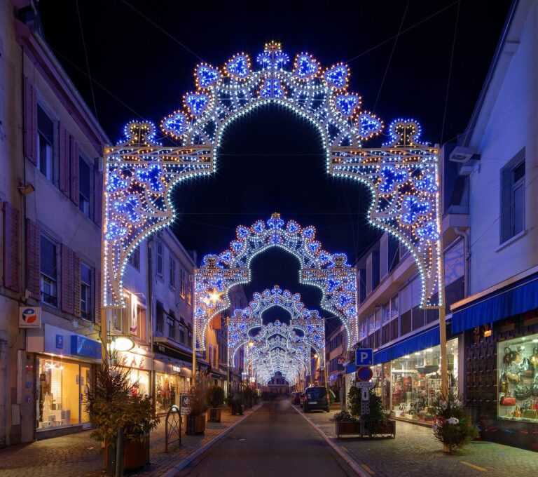 Arches lumineuses en enfilade au-dessus d’une rue commerçante de Montbéliard, de nuit