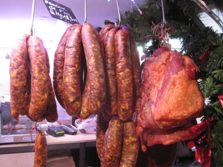 Saucisses fumées et jambons suspendus à un chalet du marché de Noël