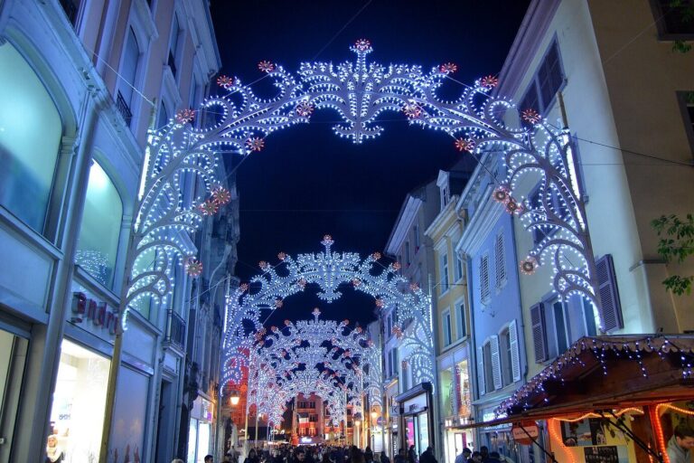 Arches lumineuses de Noël au-dessus d’une rue commerçante du centre de Mulhouse, la nuit