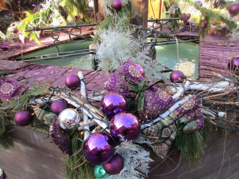 Décor de Noël en étoffe violette, boules et branchages autour d’une fontaine du marché de Mulhouse
