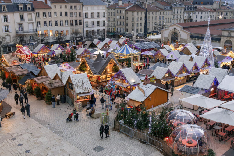 Vue plongeante sur les chalets enneigés de décor, le manège et les bulles transparentes du Grand Village de Saint-Nicolas, place Charles-III