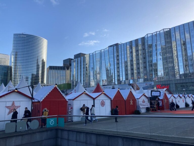 Rangée de chalets rouges et blancs du marché de Noël de La Défense au pied des immeubles de verre