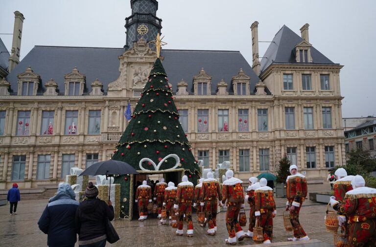 Le grand sapin décoré dressé devant l’hôtel de ville de Reims, avec un défilé de Gilles en costume vus de dos