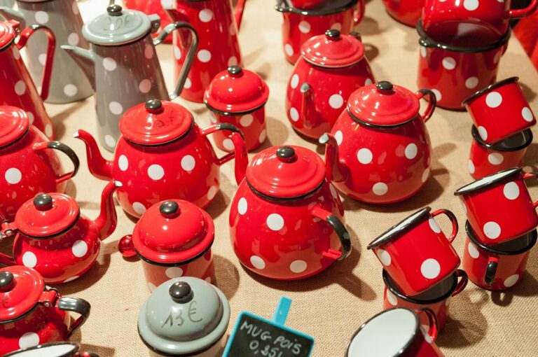 Théières et tasses émaillées rouges à pois blancs sur un étal du marché de Noël