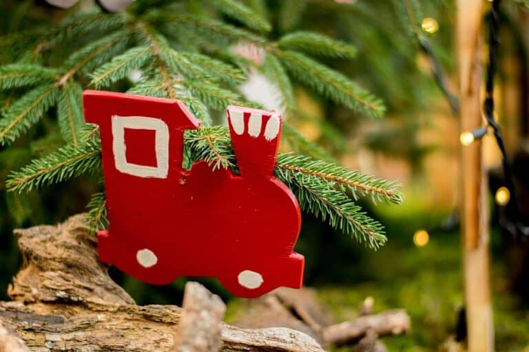 Décoration de Noël en bois en forme de petite locomotive rouge, posée dans un sapin