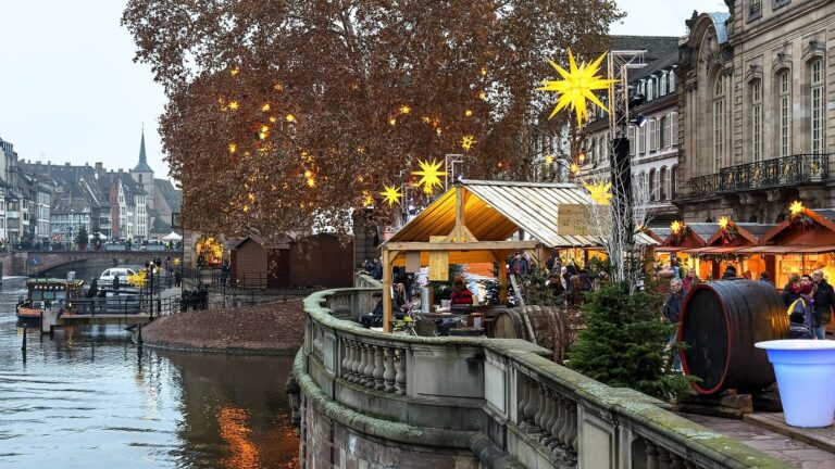 Chalets du marché et étoiles lumineuses sur une terrasse au bord de l’Ill, en fin d’après-midi