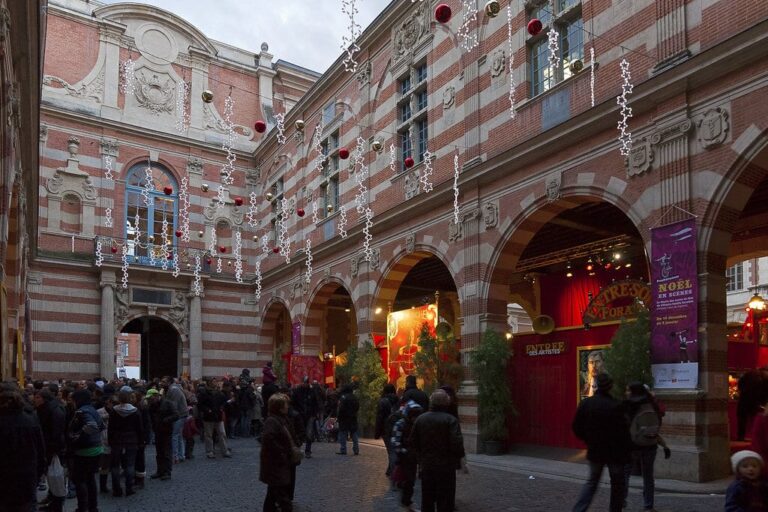 La cour du Capitole décorée de boules rouges pour les fêtes, avec ses arcades en brique et pierre
