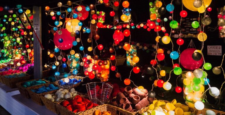 Guirlandes de boules lumineuses multicolores suspendues au-dessus d’un stand du marché de Noël
