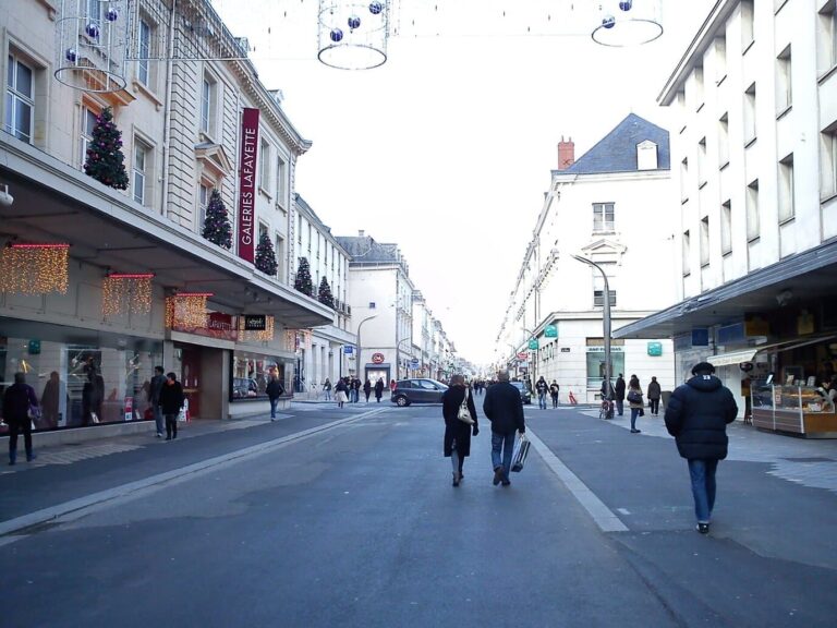 La rue Nationale décorée pour Noël, avec des suspensions et des sapins aux balcons, en journée