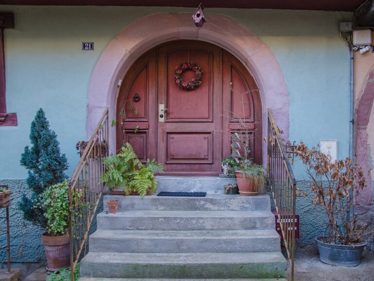 Porte en bois cintrée d’une maison d’Eguisheim ornée d’une couronne de Noël, en haut d’un perron