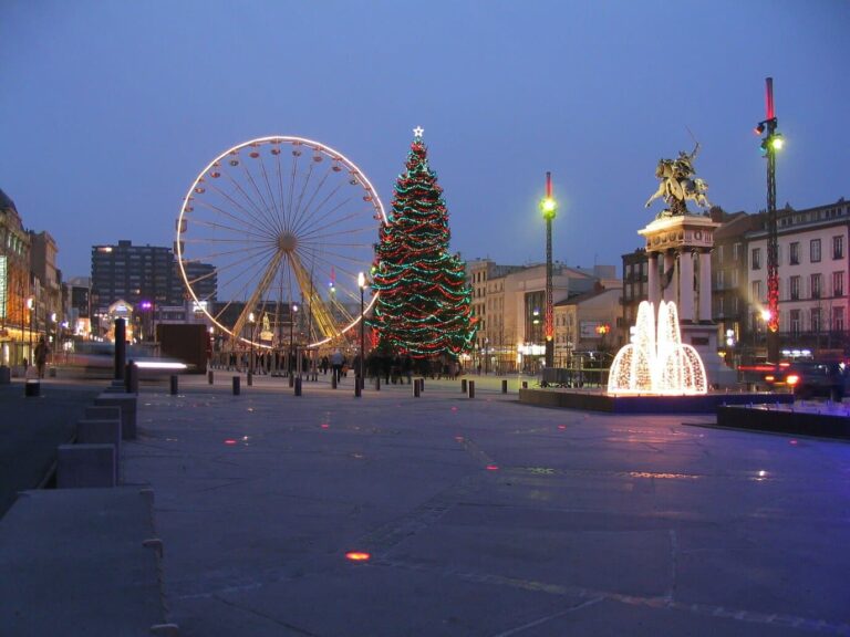 La place de Jaude au crépuscule, avec la grande roue, le sapin aux guirlandes rouges et vertes, la fontaine lumineuse et la statue de Vercingétorix