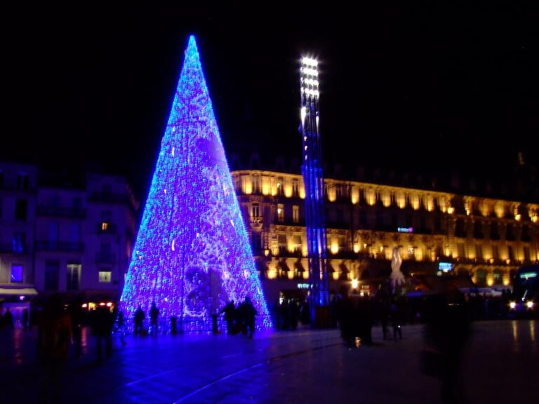 Cône lumineux bleu dressé comme un sapin sur la place de la Comédie, de nuit