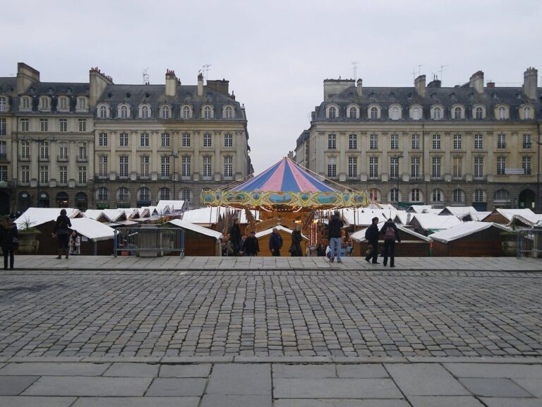 Vue d’ensemble de la place du Parlement avec ses chalets aux toits blancs et un manège, par temps gris