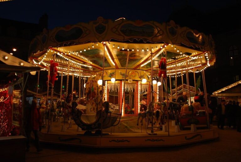 Manège ancien illuminé de guirlandes dorées sur le marché de Noël, de nuit