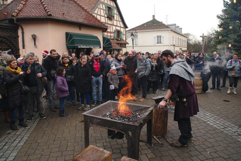 Un forgeron en costume médiéval attise son feu devant les visiteurs du marché de Noël médiéval de Ribeauvillé