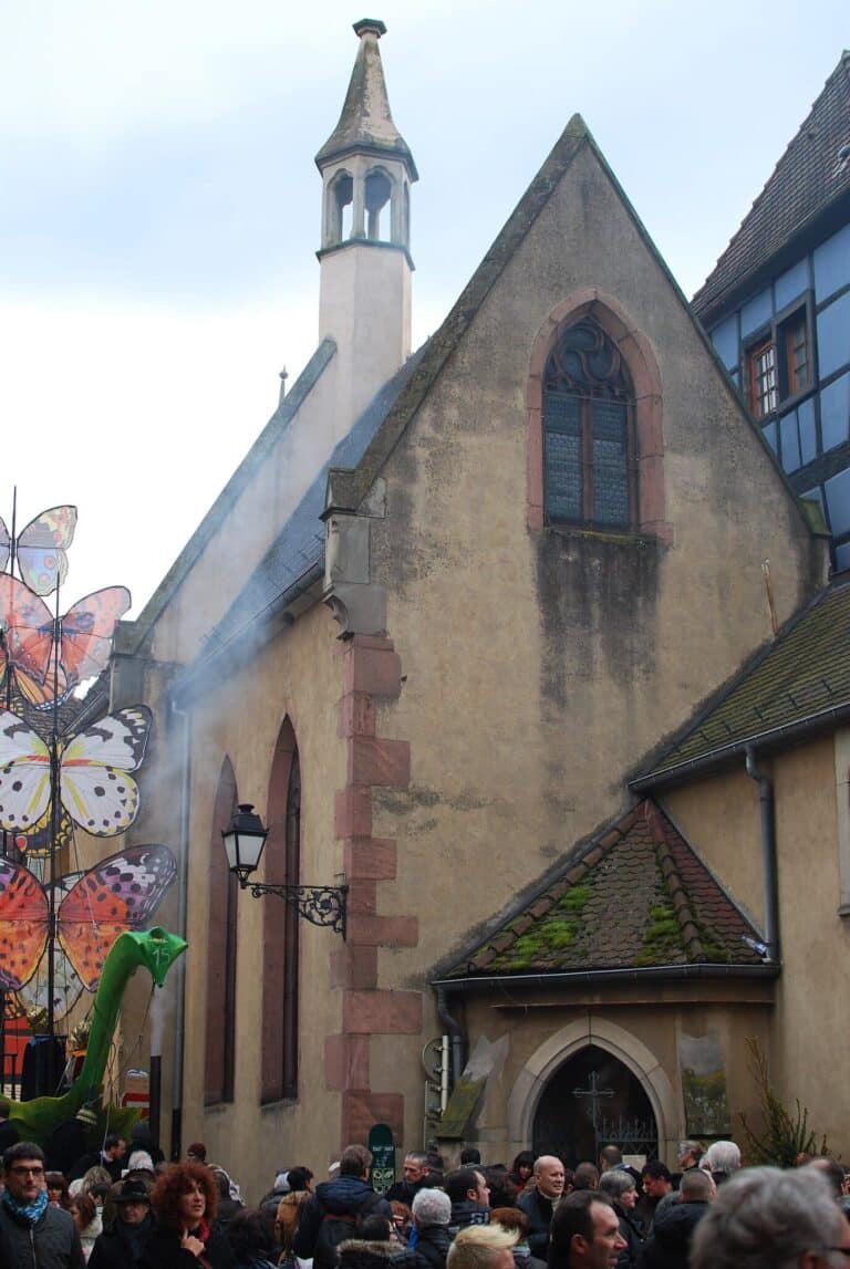 La chapelle Sainte-Catherine de Ribeauvillé pendant la fête de Noël médiévale, décor de grands papillons et foule à ses pieds