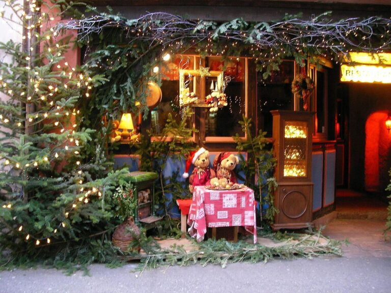 Vitrine de Noël décorée d’un sapin illuminé, de guirlandes et d’oursons attablés