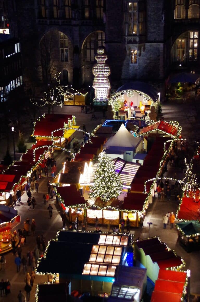 Le marché de Noël vu d’en haut, la nuit, avec ses allées de chalets éclairés et un sapin illuminé au centre