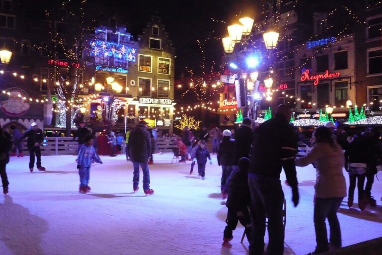 Patineurs sur la patinoire du Leidseplein, le soir, sous les guirlandes lumineuses et les façades illuminées