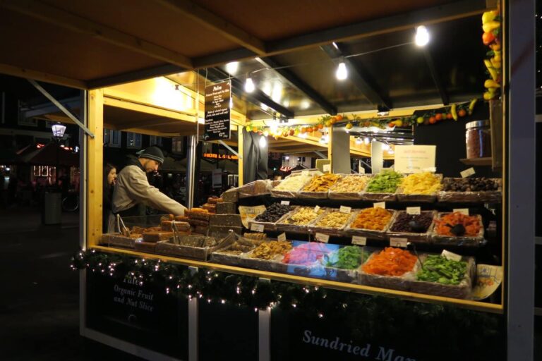 Chalet éclairé d’un marché de Noël d’Amsterdam garni de fruits secs, de nougats et de guirlandes de sapin, la nuit