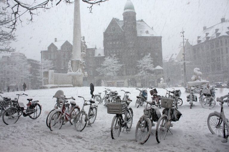La place du Dam sous la neige, avec ses vélos enneigés au pied du Monument national
