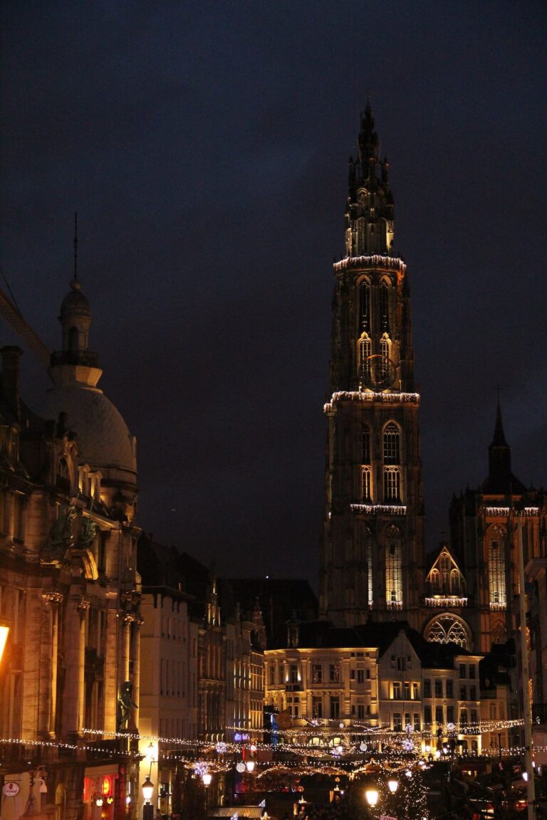 La tour gothique de la cathédrale Notre-Dame d’Anvers illuminée la nuit, au-dessus des lumières des rues du centre