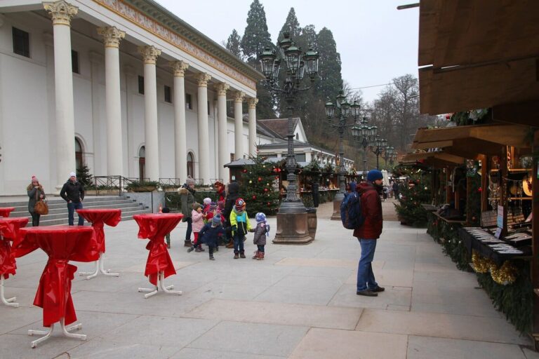 Allée du marché de Noël au pied des colonnes du Kurhaus de Baden-Baden, avec mange-debout drapés de rouge et chalets décorés