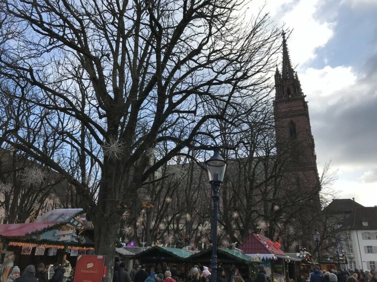 Chalets du marché de Noël du Münsterplatz sous les arbres, avec la tour de la cathédrale de Bâle en arrière-plan