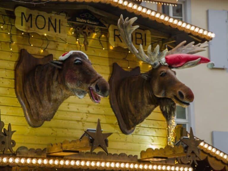 Deux têtes d’élans animées coiffées de bonnets de Noël sur la façade d’un chalet du marché de Noël de Bâle
