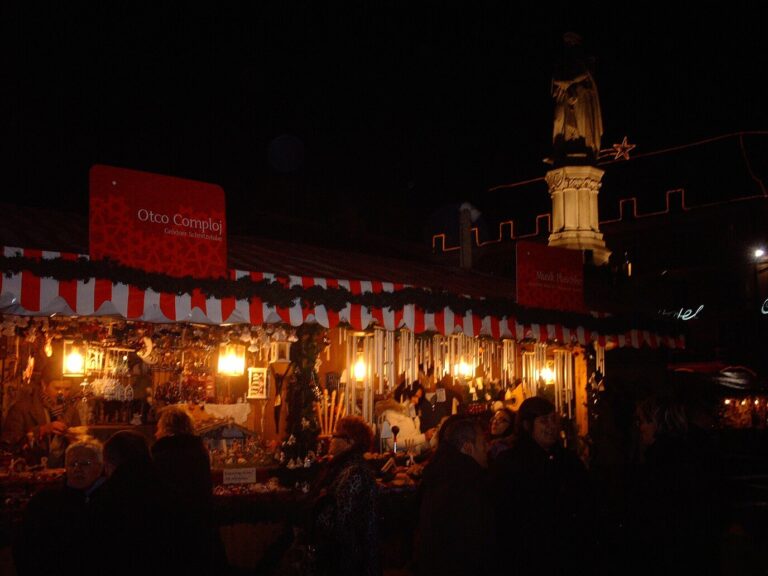 Chalets éclairés du marché de Noël de Bolzano la nuit, au pied de la statue de Walther von der Vogelweide