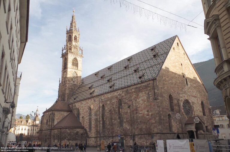 La cathédrale de Bolzano et son toit de tuiles vernissées vue depuis la via della Posta, sous des guirlandes lumineuses de décembre
