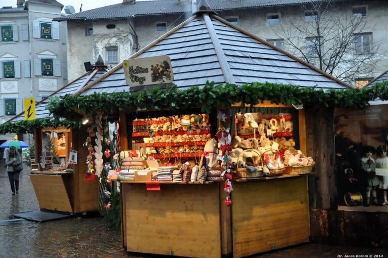 Chalet de bois du marché garni de décorations de Noël et de friandises, sous une guirlande de sapin