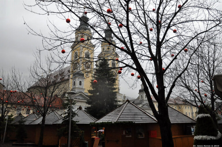 La cathédrale de Bressanone derrière un arbre décoré de boules rouges et les toits des chalets
