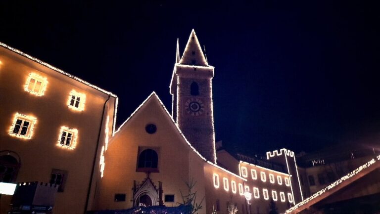 Façades et clocher soulignés de guirlandes lumineuses dans le centre de Brunico, la nuit