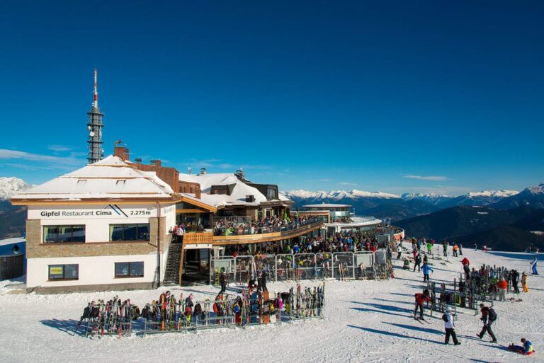 Le sommet du Plan de Corones enneigé au-dessus de Brunico, ses refuges et ses skieurs sous un ciel bleu